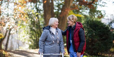 Pflegerin geht mit Senioren draußen im Herbst spazieren