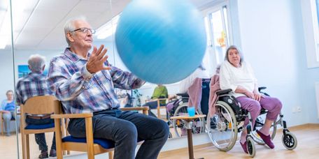 Senioren spielen mit einem blauen Pezziball