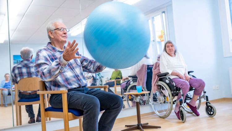 Senioren spielen mit einem blauen Pezziball