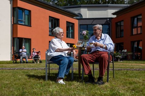 gemeinsam draußen im Garten Zwei Senioren sitzen im Vorgarten der Seniorenrsidenz auf Stühlen