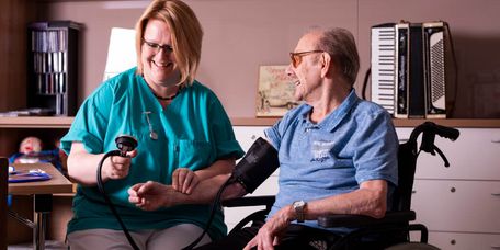 Pflegekraft misst bei einem Bewohner den Blutdruck