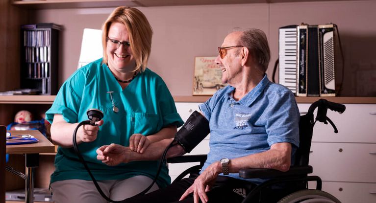 Pflegekraft misst bei einem Bewohner den Blutdruck