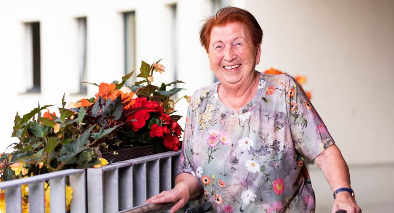 Bewohnerin mit roten Haaren steht auf dem Balkon