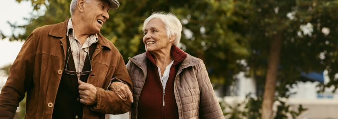 lachendes älteres Paar spaziert gemeinsam im herbstlichen Park